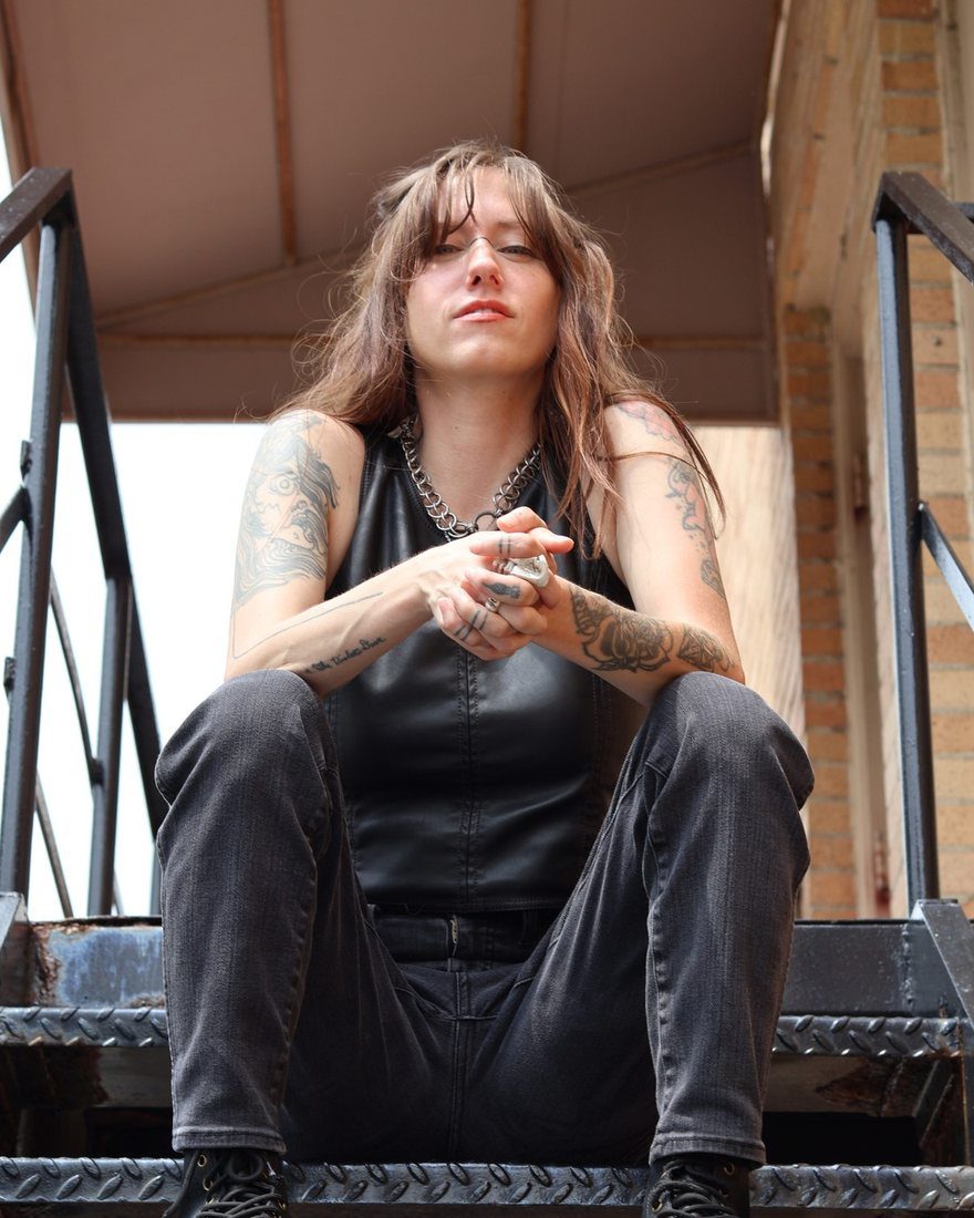 Bridgette Kidd sitting on a metal fire escape stair, looking down at the camera